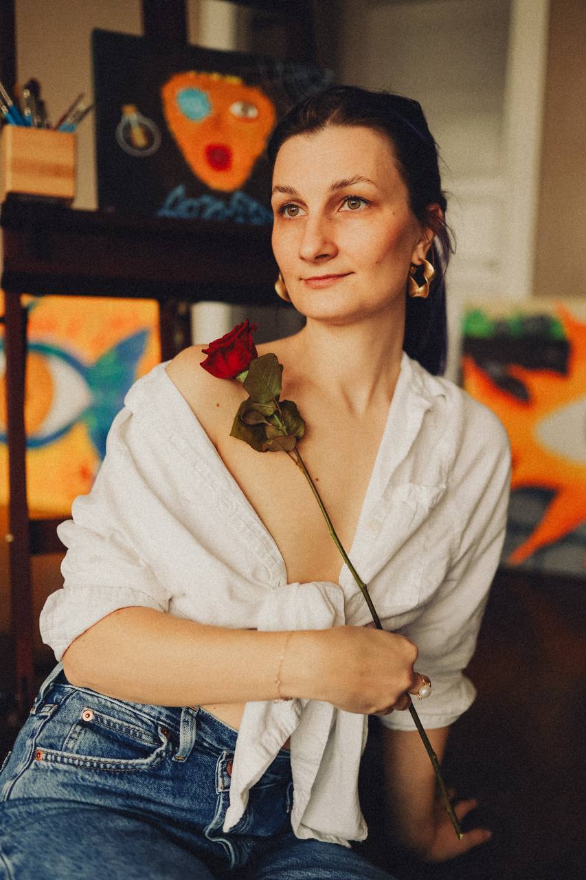 Карина Ask с розой на фоне своих работ